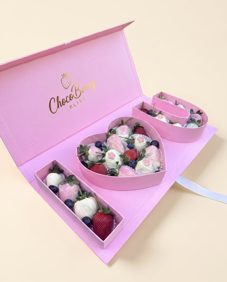 Pale pink gift box with compartments shaped as the letters I, a heart and U, filled with strawberries and blueberries