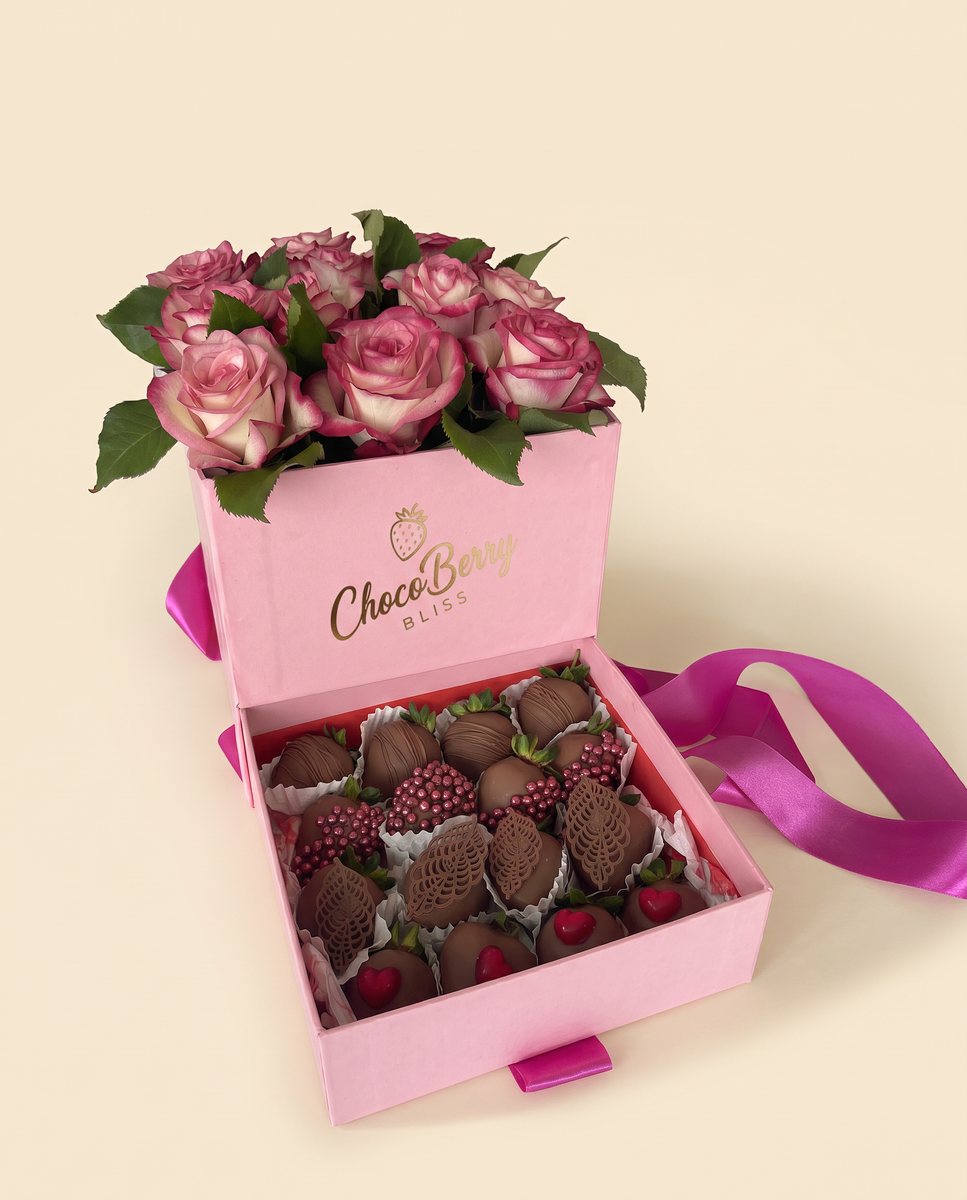 Pink two-tier gift box: fresh roses above, chocolate-covered strawberries in paper cups below