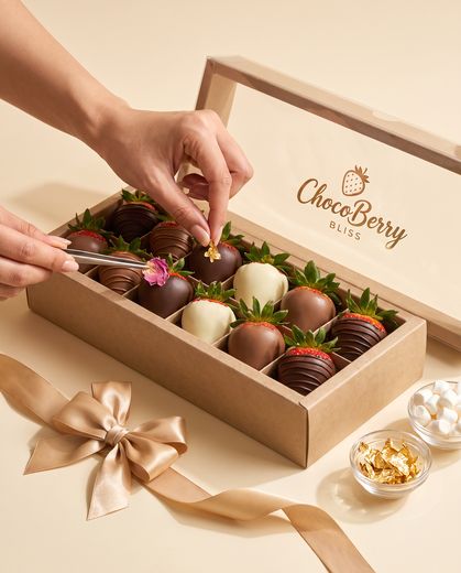 Hands packing chocolate strawberries into a gift box